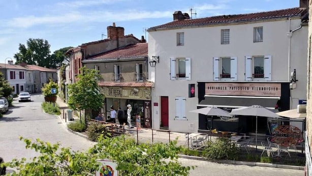 A street view with buildings, outdoor seating, and a sign for a patisserie. - Duplex in charming neighborhood overlooking chateau, close to downtown and all amenities (Clisson)