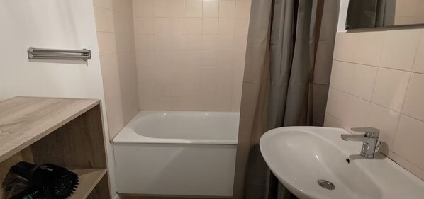 Un baño con bañera, lavamanos y cortina de ducha.