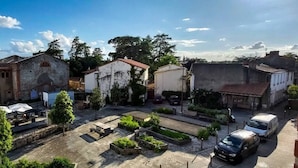 A street view with buildings, a paved square with benches, and a parked car. - Duplex in charming neighborhood overlooking chateau, close to downtown and all amenities (Clisson)
