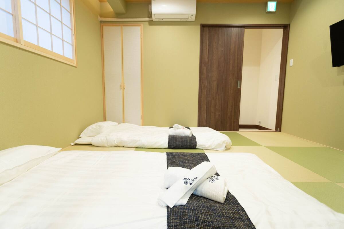 A hotel room with two beds, a wooden door, and a window with a view.