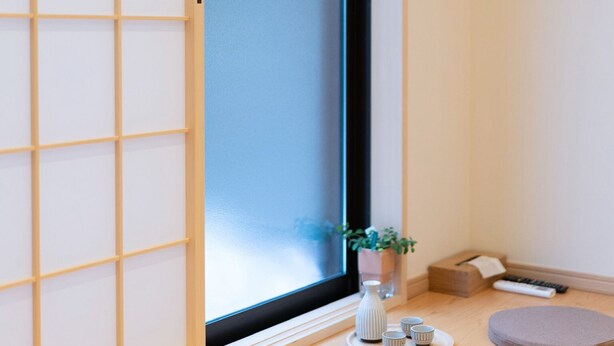 A room with a sliding door, a small table with cups and a vase, and two round stools. - HANASTAY YAMA (Osaka)