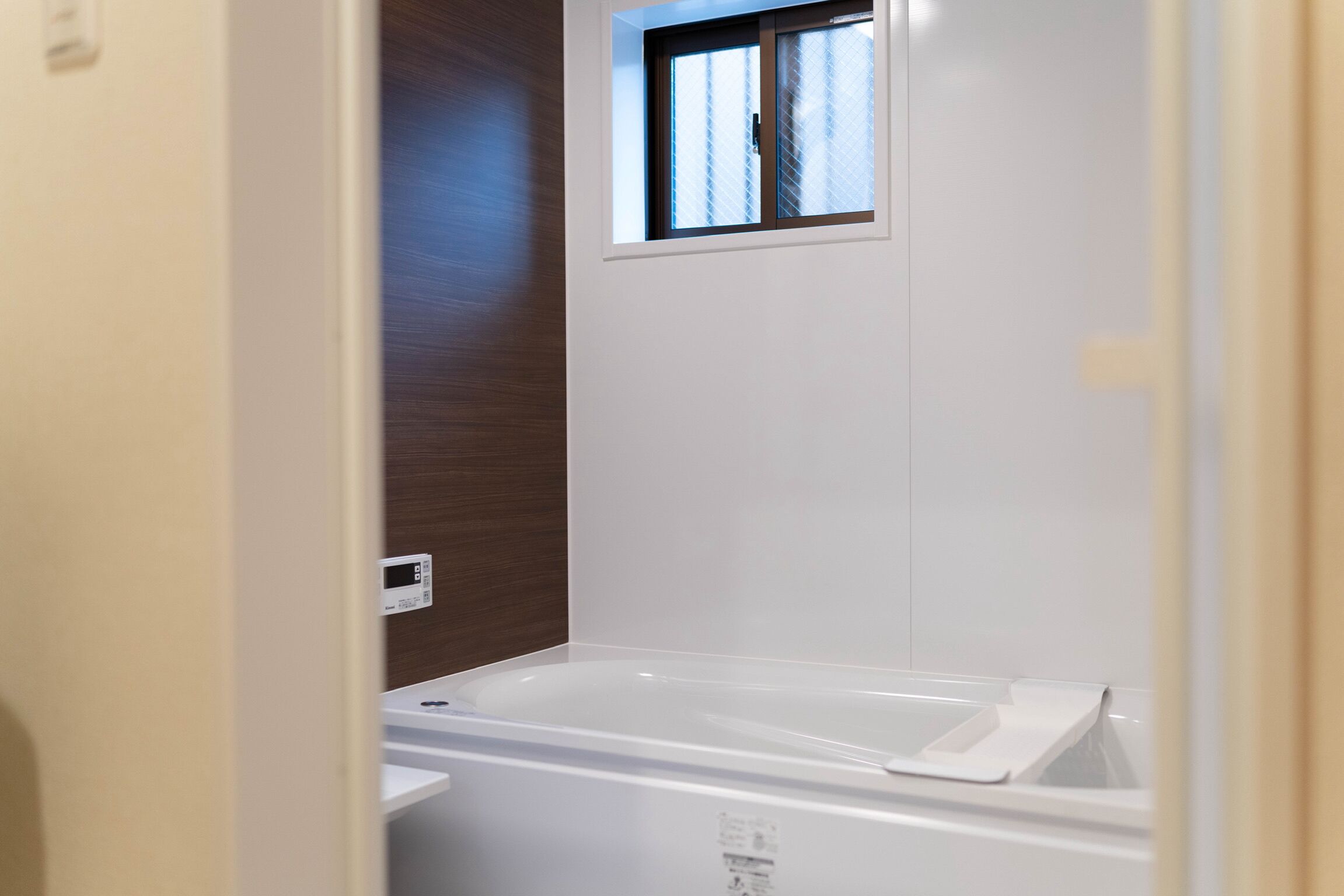 A bathroom with a bathtub, a window, and a wooden wall.