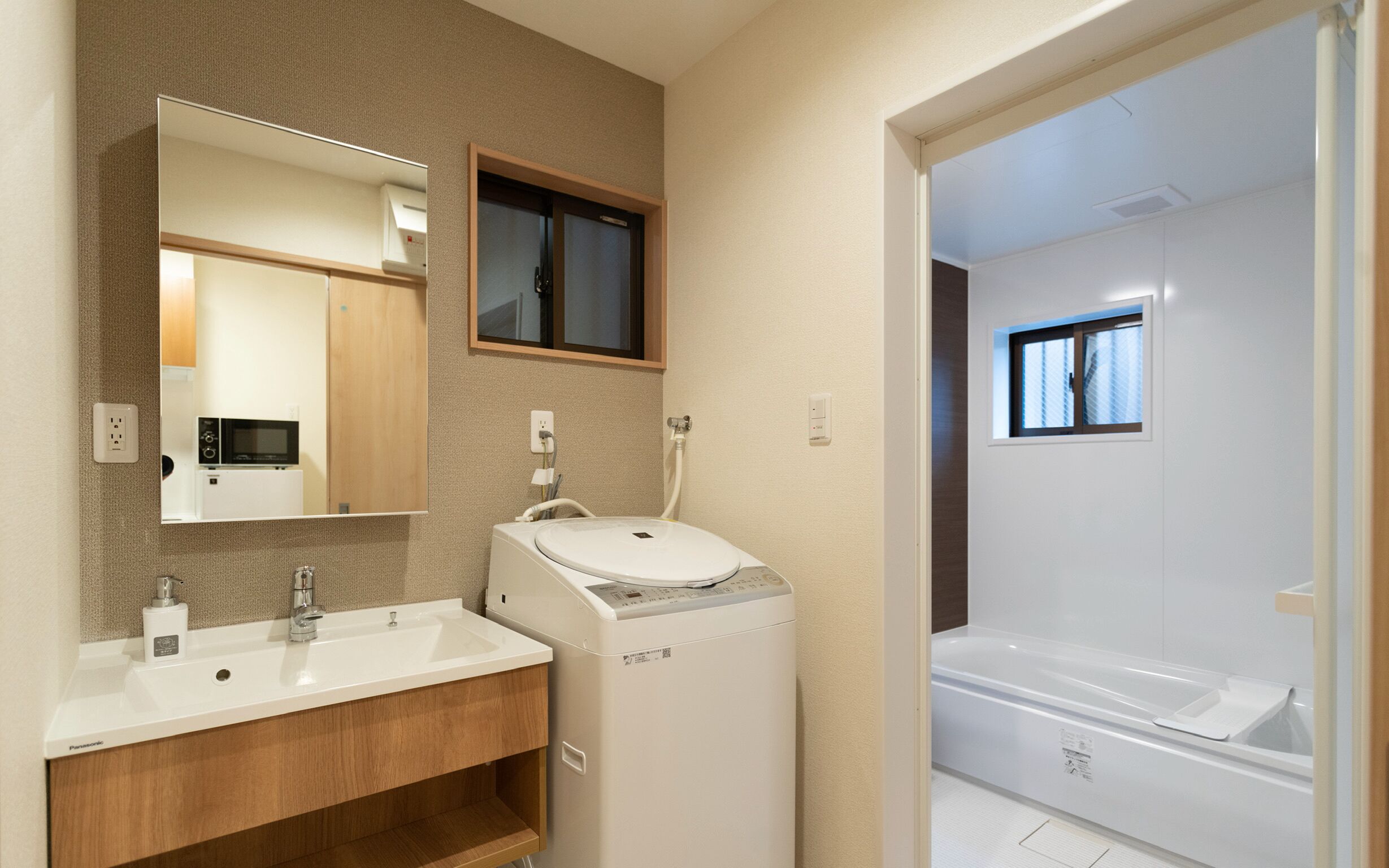 Une salle de bain avec un lavabo, un miroir et un lave-linge blanc.