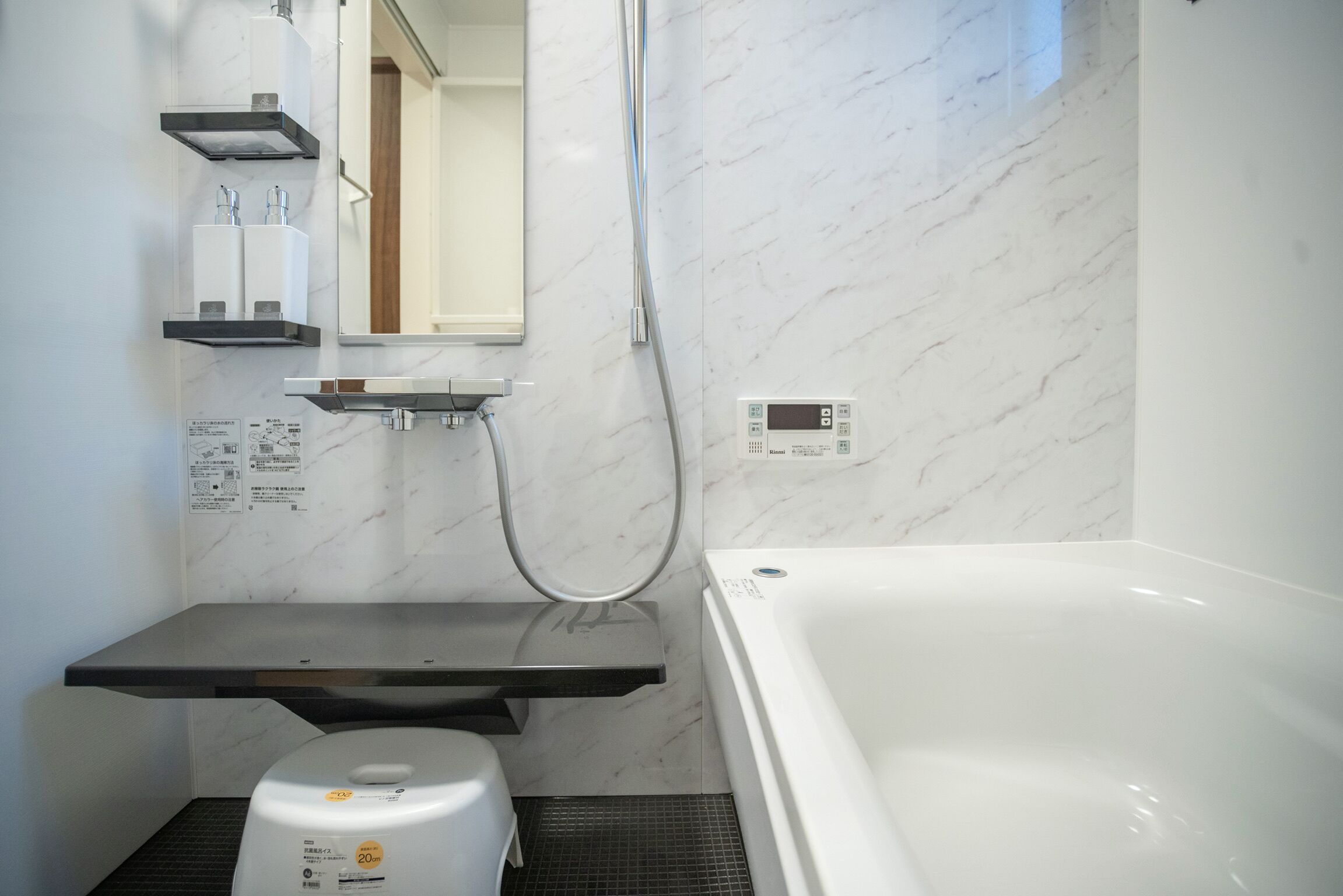Ein modernes Badezimmer mit einer weißen Badewanne, einem integrierten Waschbecken und einer Duschkabine.