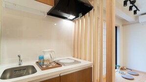 A modern kitchen with a stainless steel sink, wooden cabinets, a coffee maker, and a tray with glasses and a bottle. - HANASTAY YAMA (Osaka)