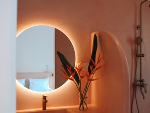 A bathroom with a large mirror, a sink, a shower, and a vase with flowers. - Animals Ahangama (Ahangama)