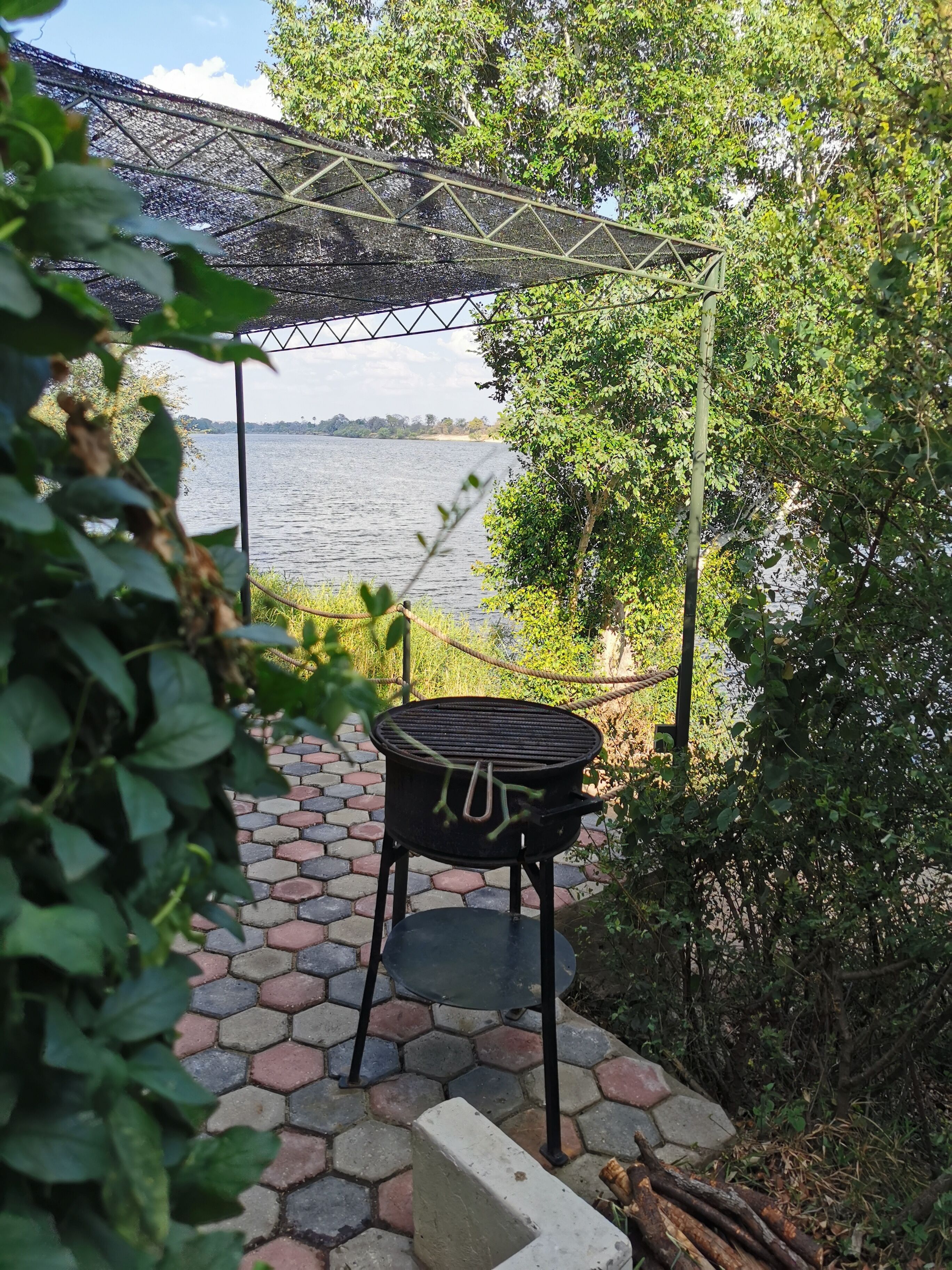 Ein Grill unter einer Pergola mit Blick auf einen See.