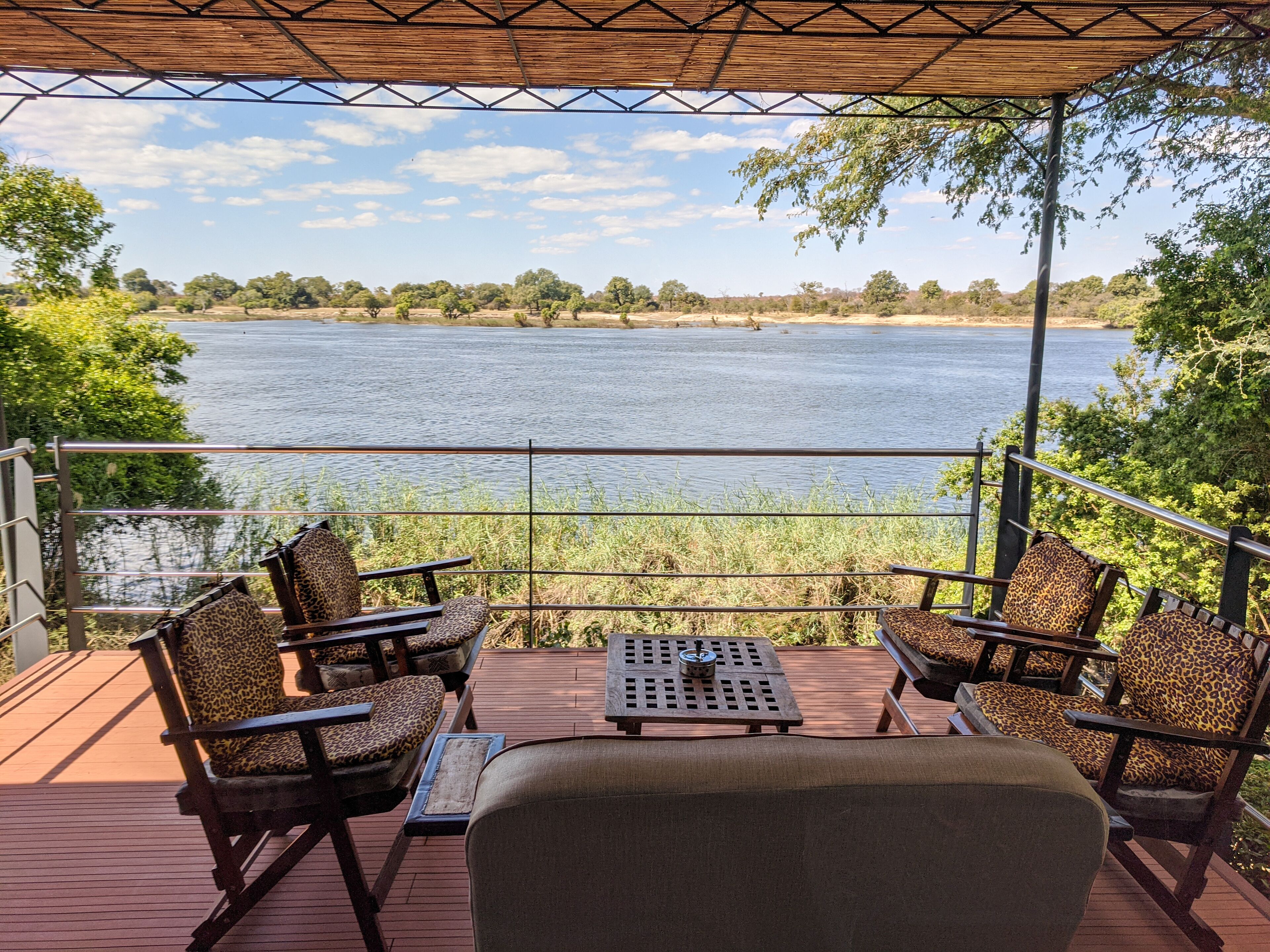 A deck with outdoor furniture overlooking a lake, surrounded by trees.