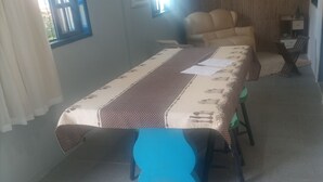 A dining area with a table covered in a patterned tablecloth, a chair, and a sofa.