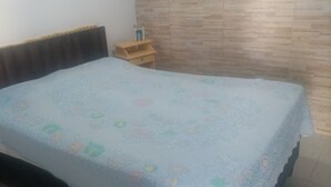 A bedroom with a bed, a wooden headboard, a nightstand, and a brick-patterned wall.