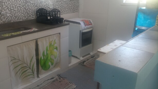 A kitchen with a tiled backsplash, a microwave, a sink, and a cabinet with a leaf-patterned door.