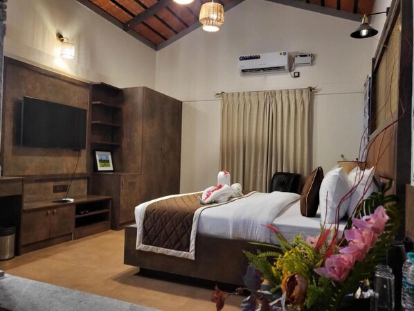 A modern hotel room with a large bed, a flat-screen TV, a built-in shelf, and a ceiling fan.
