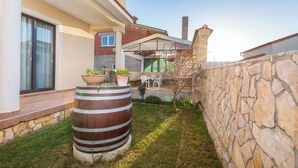 Une maison moderne avec un mur en pierre, une grande cuve et une terrasse dotée de mobilier d’extérieur.
