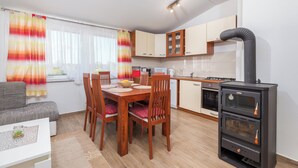 Une cuisine compacte comprenant un fourneau, des placards et un coin repas avec des chaises et une table.