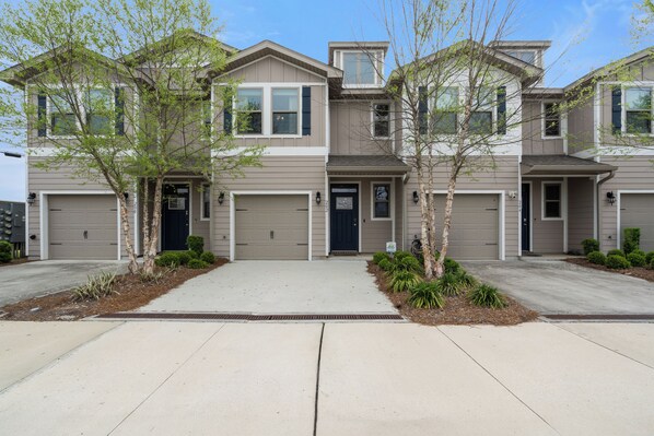 A two-story townhouse with a garage, a front porch, and a driveway.