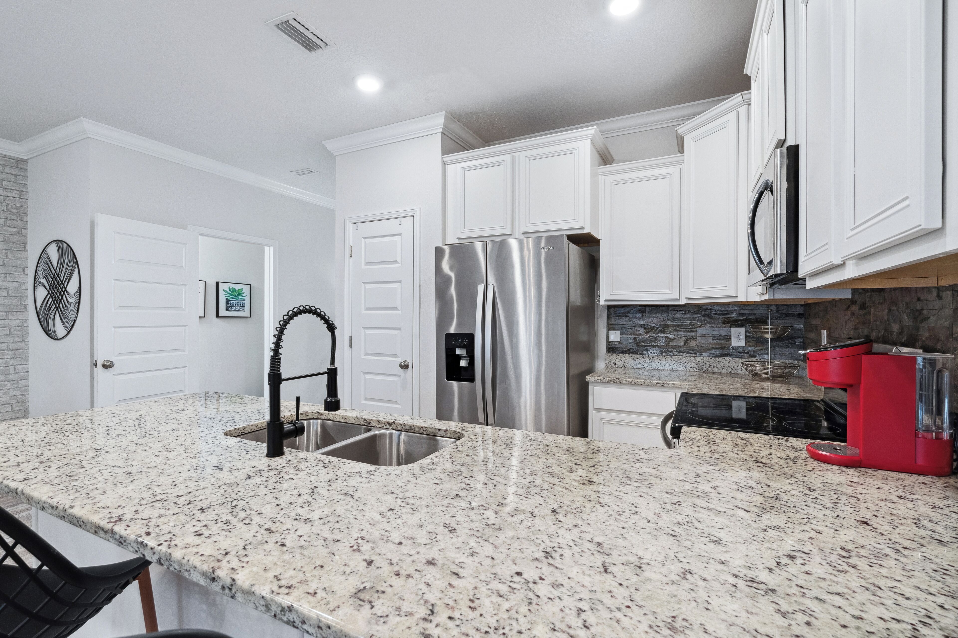 A modern kitchen with white cabinets, stainless steel appliances, and a granite countertop.