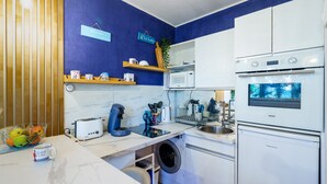 A compact kitchen with a washing machine, a microwave, a toaster, and a sink.