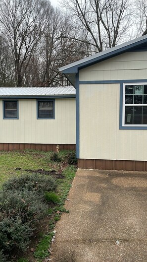 A single-story building with a flat roof, a small front porch, and a window with a sign that reads "R3". - Tranquil mobile home with AC in charming Sardis (Sardis)