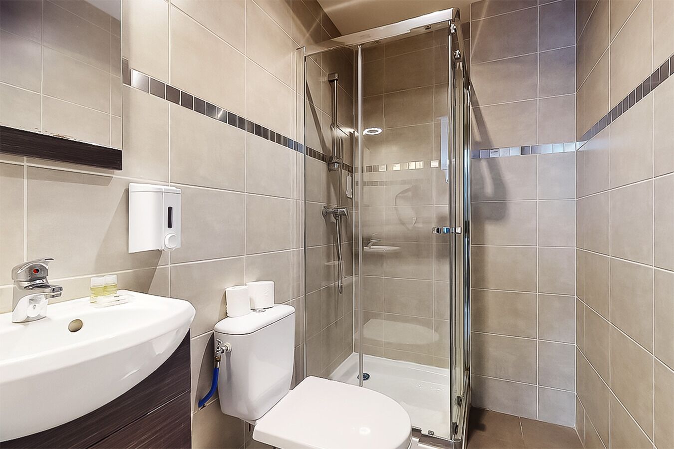 Ein modernes Badezimmer mit einer Duschkabine, einem weißen Waschbecken und einer Toilette.
