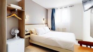 A modern hotel room with a bed, a bedside table, a wardrobe, and a wall-mounted TV.