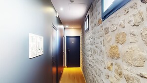 A hallway with a stone wall on one side, a door labeled '23', and a poster on the wall.