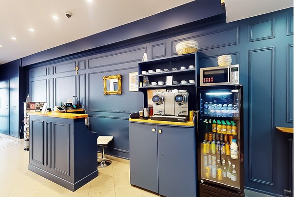 A bar area with a coffee machine, a beverage dispenser, and a small seating area. - Hotel de Menilmontant (Paris)