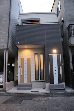 A modern building with a flat roof, two symmetrical doors, and a small set of steps leading to the entrance. - HANASTAY MATSU (Osaka)