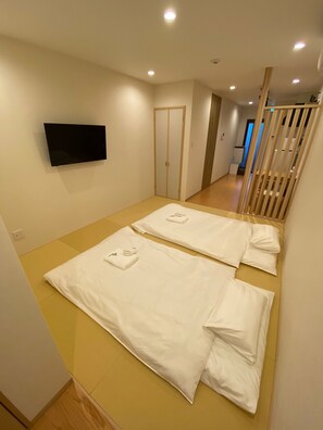 Une chambre d’hôtel avec un lit, un téléviseur fixé au mur et un escalier en bois.