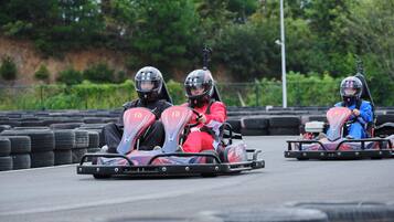 Tres karts de carreras en una pista, con neumáticos y una zona verde de fondo.