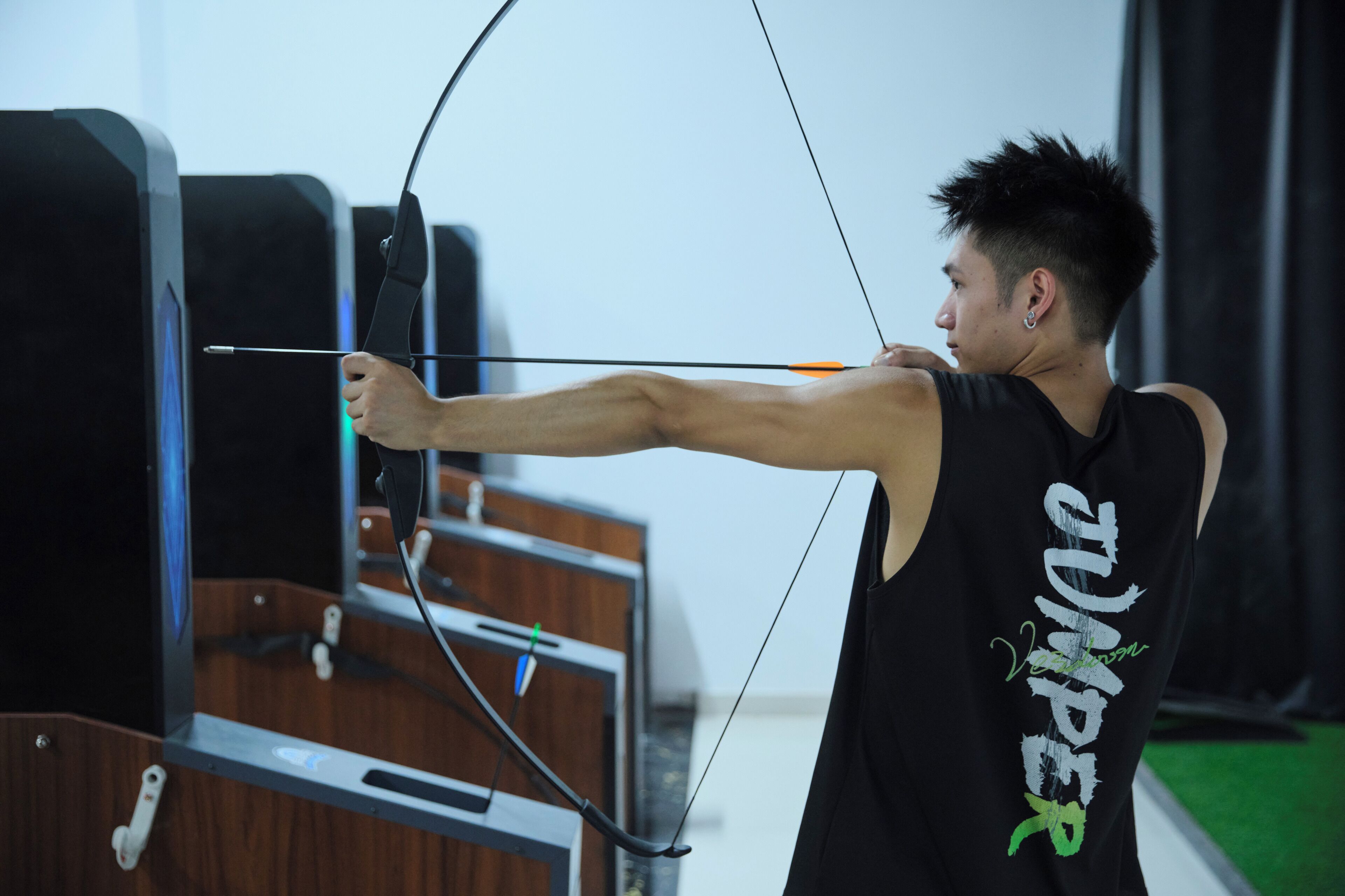 Una persona practicando tiro con arco en un espacio interior.