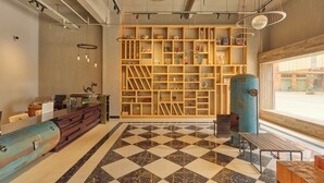 Ein modernes Interieur mit einem Schachbrettfußboden, Holzregalen mit verschiedenen Gegenständen, einem Schreibtisch mit einem Computer und einem großen Fenster.