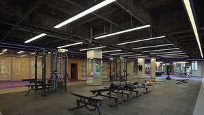 Ein Fitnessstudio mit verschiedenen Trainingsgeräten, darunter Gewichtbänke und ein Squat-Gestell.