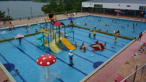 Ein Schwimmbecken mit mehreren Bahnen, Wasserrutschen und einem Rettungsschwimmerstand.