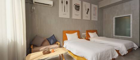 Een moderne hotelkamer met twee bedden, een kleine zithoek, een houten tafeltje en kunst aan de muur.