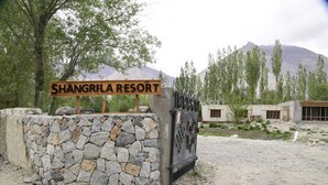 Skilt for Shangrila Resort med en stenvæg og en port.