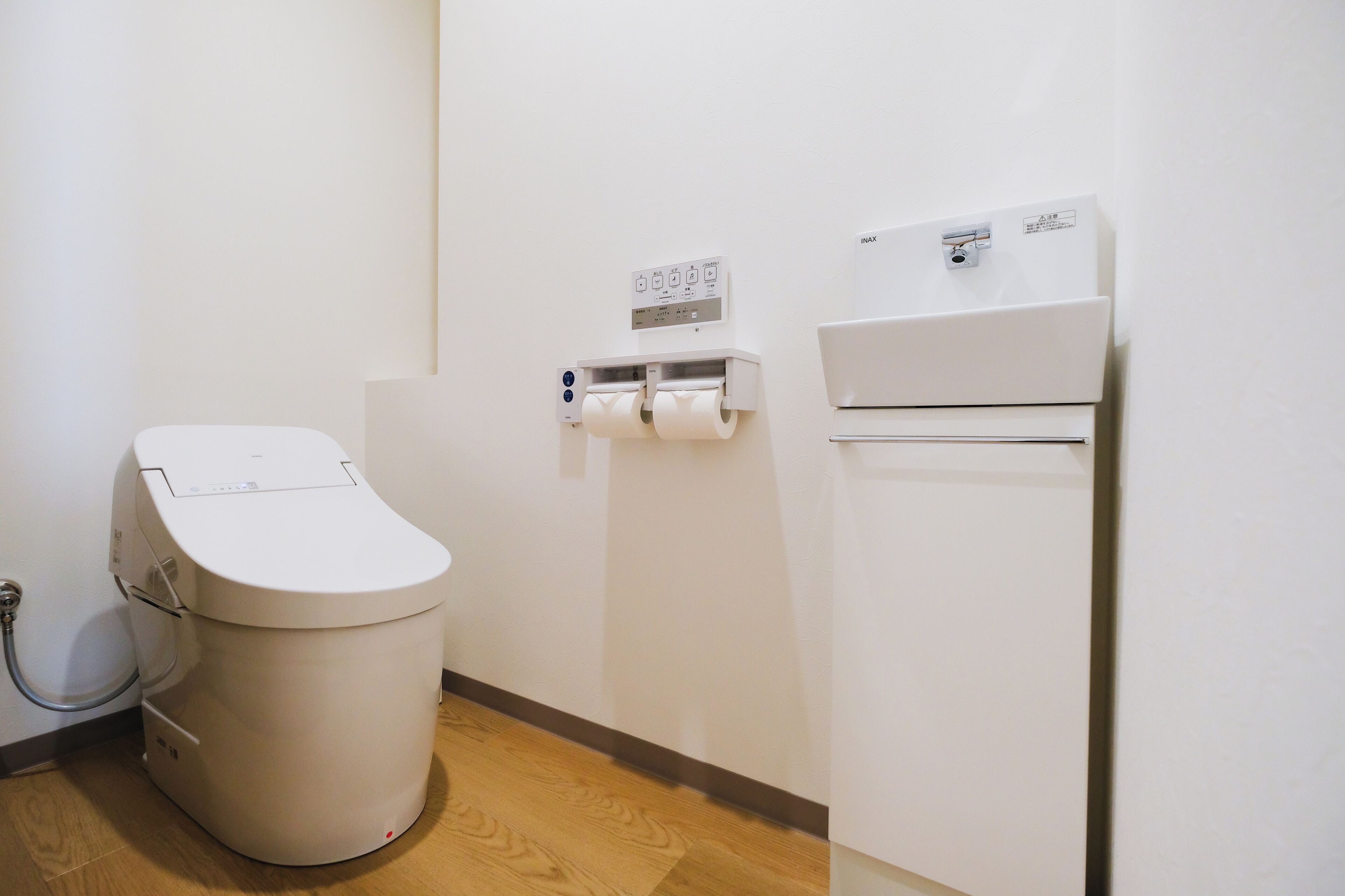 A small, modern bathroom with a toilet, a paper towel dispenser, and a wall-mounted air conditioner.