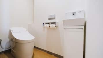 A small, modern bathroom with a toilet, a paper towel dispenser, and a wall-mounted air conditioner.