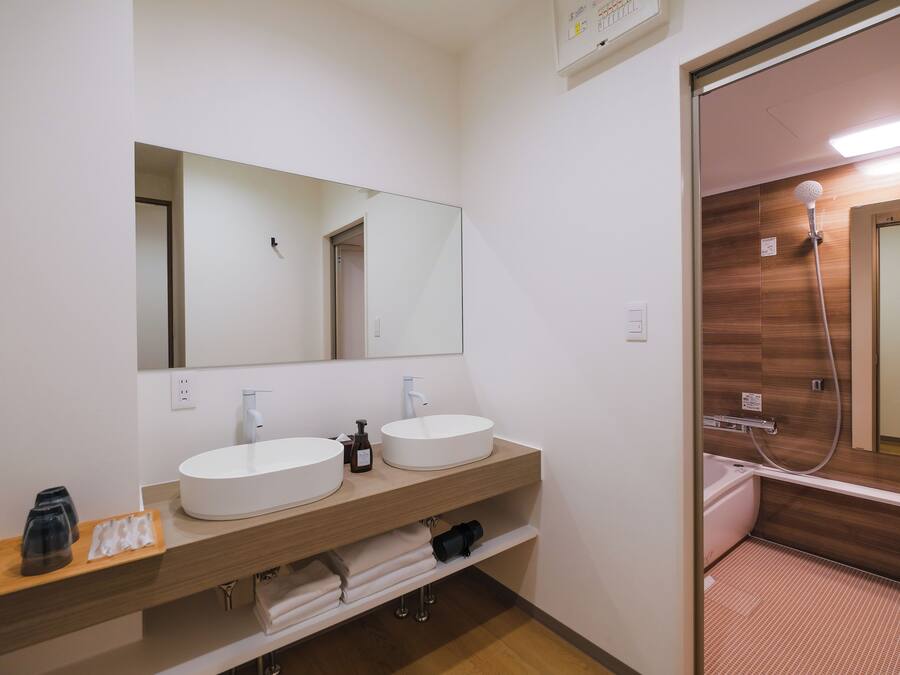 A modern bathroom with two sinks, a large mirror, and a shower area.