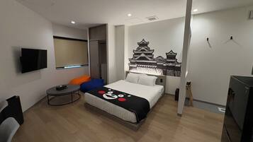 A modern hotel room with a bed, a TV, a small table, and a wall-mounted air conditioner.