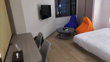 Een hotelkamer met een bed, een bureau, twee stoelen, een klein tafeltje en een televisie aan de muur.