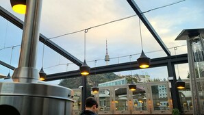 A modern interior with hanging pendant lights and a view of a tower in the background.