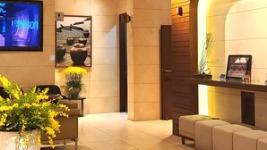 A modern reception area with a flat-screen TV, a reception desk, a seating area, and a potted plant.