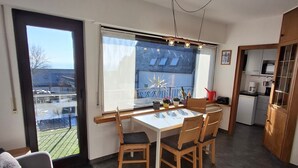 Une cuisine moderne avec un coin repas, un canapé et une vue dégagée grâce à de grandes fenêtres.