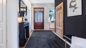 A hallway with a dark carpet, a wooden door, a mirror, and a framed artwork on the wall. - Holiday Apartment 'Landhaus Heiddorf' with 2 Comfortable Bedrooms, Terrace with BBQ & Sun Loungers (Neu Kaliß)