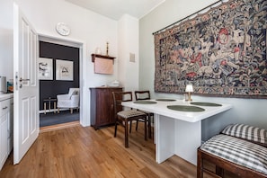 A dining area with a white table, chairs, and a large tapestry on the wall. - Holiday Apartment 'Landhaus Heiddorf' with 2 Comfortable Bedrooms, Terrace with BBQ & Sun Loungers (Neu Kaliß)