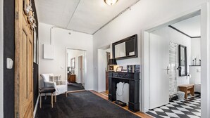 A hallway with a black and white checkered floor, a black fireplace, and a white sofa. - Holiday Apartment 'Landhaus Heiddorf' with 2 Comfortable Bedrooms, Terrace with BBQ & Sun Loungers (Neu Kaliß)