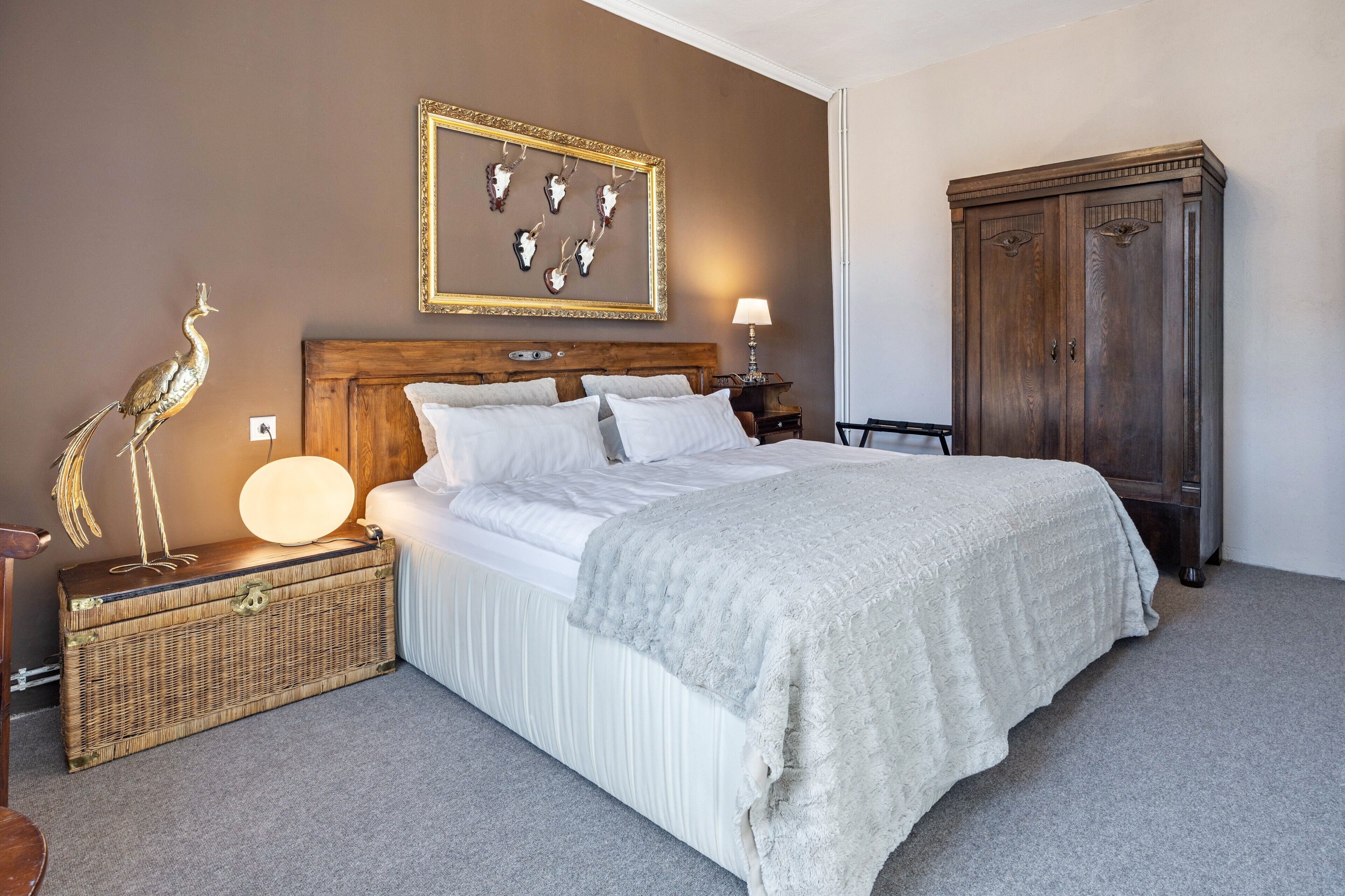 Un dormitorio con cama, mesita de noche, lámpara, cómoda y decoración en la pared.