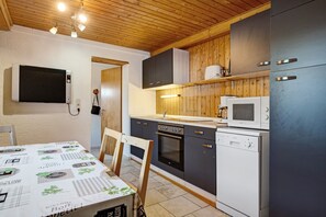 Een moderne keuken met houten kastjes, een magnetron, oven en vaatwasser.