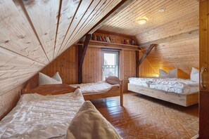 Dormitorio estilo loft con dos camas, paredes de madera, techo inclinado y una ventana.