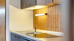 A modern kitchen with a stainless steel sink, wooden panel wall, and built-in oven.